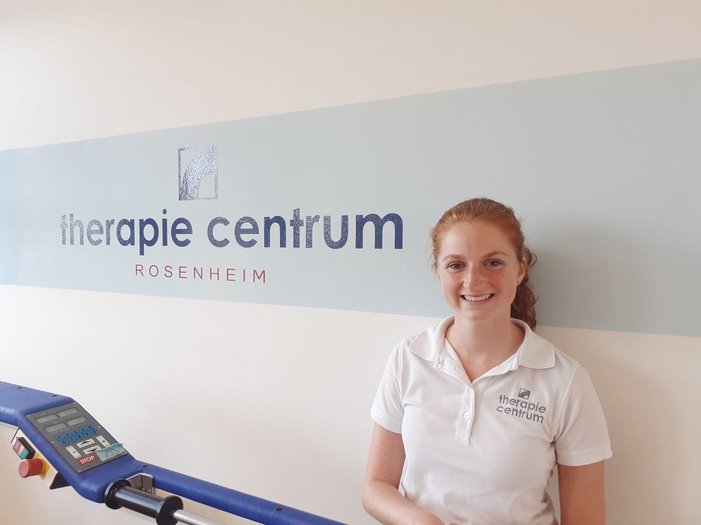 Maria steht vor einer Wand mit dem Firmenlogo