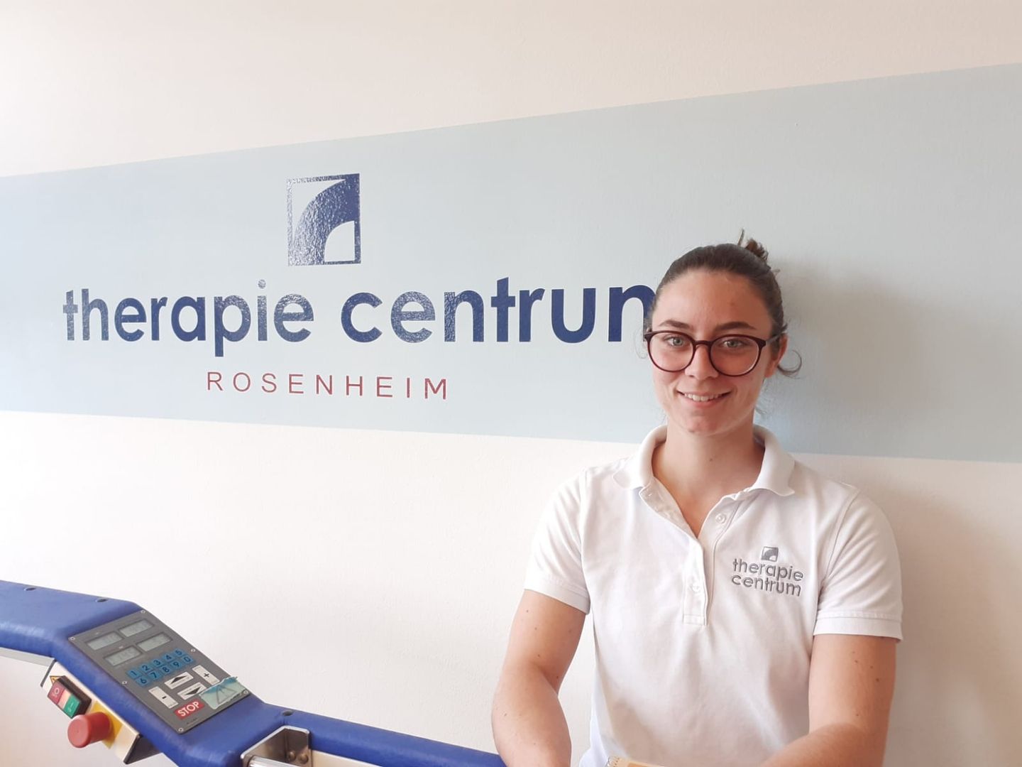 Nina steht vor einer Wand mit dem Firmenlogo